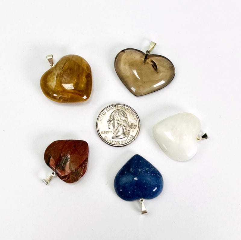 heart shaped stone pendants with a silver bail next to a quarter for size reference 