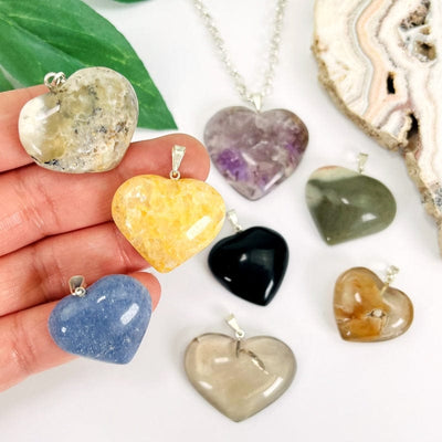 multiple stone heart shaped pendants in hand for size reference 