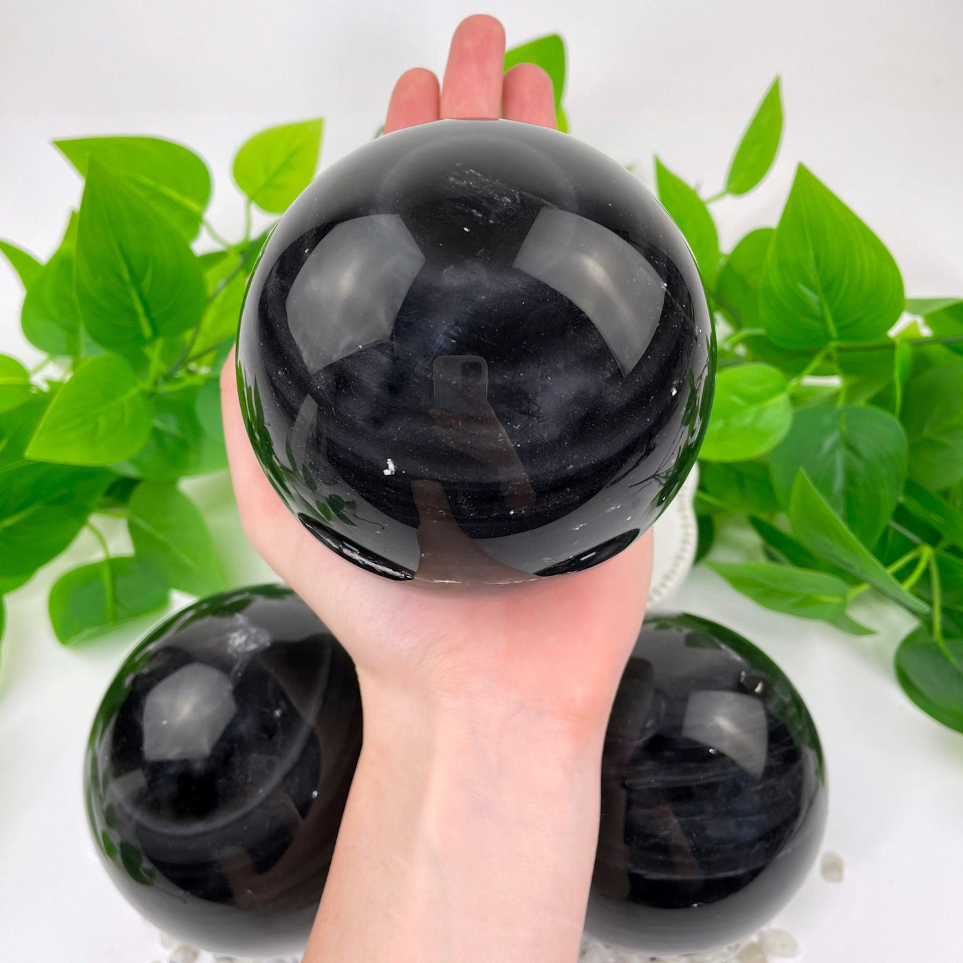 one black agate polished sphere in hand for size reference