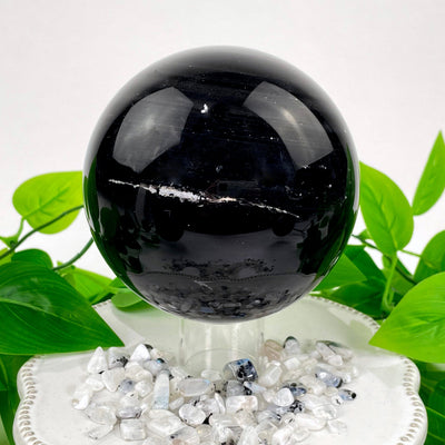 close up of one black agate polished sphere on display on clear stand for details