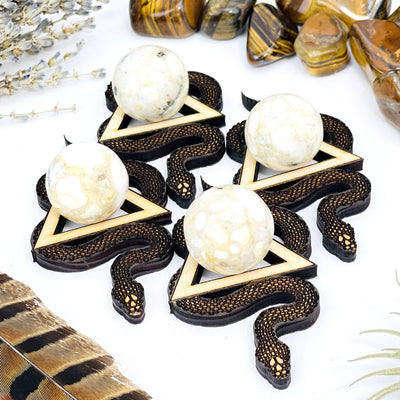 four snake wooden sphere stands on display with one sphere in the center of each