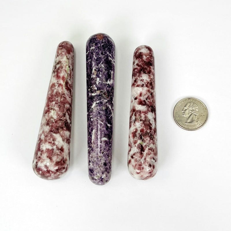 close up of the lepidolite massage wands next to a quarter for size reference 