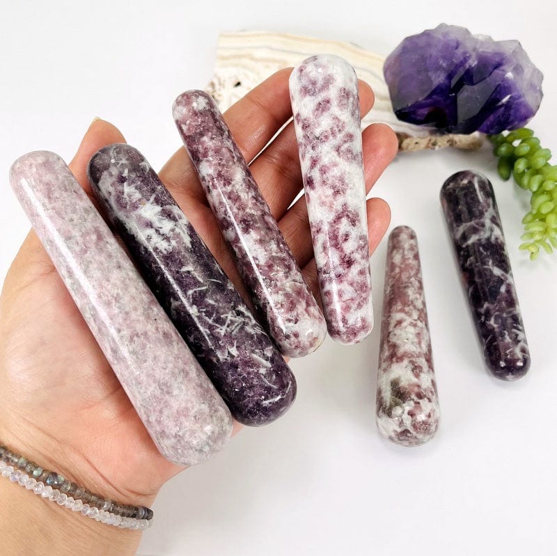 multiple lepidolite massage wands in hand displaying the different variations 