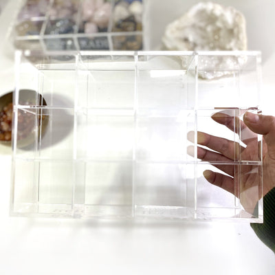 An empty acrylic box in hand showing the top view.