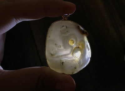 An Enhydro Pendant held up to a light to show enhydro.