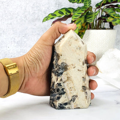 Hand comparing size to the Feldspar with Black Tourmaline Polished Point