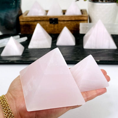 pink calcite pyramids in hand showing the size differences 