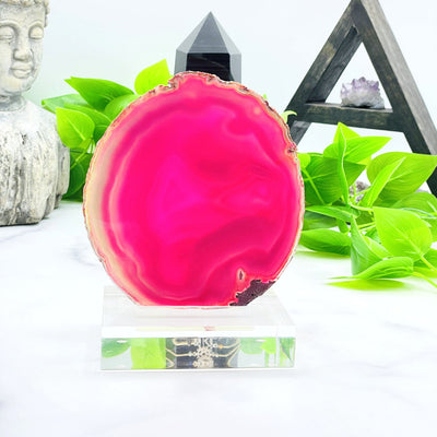 A vibrant pink agate slice on acrylic stand with white background