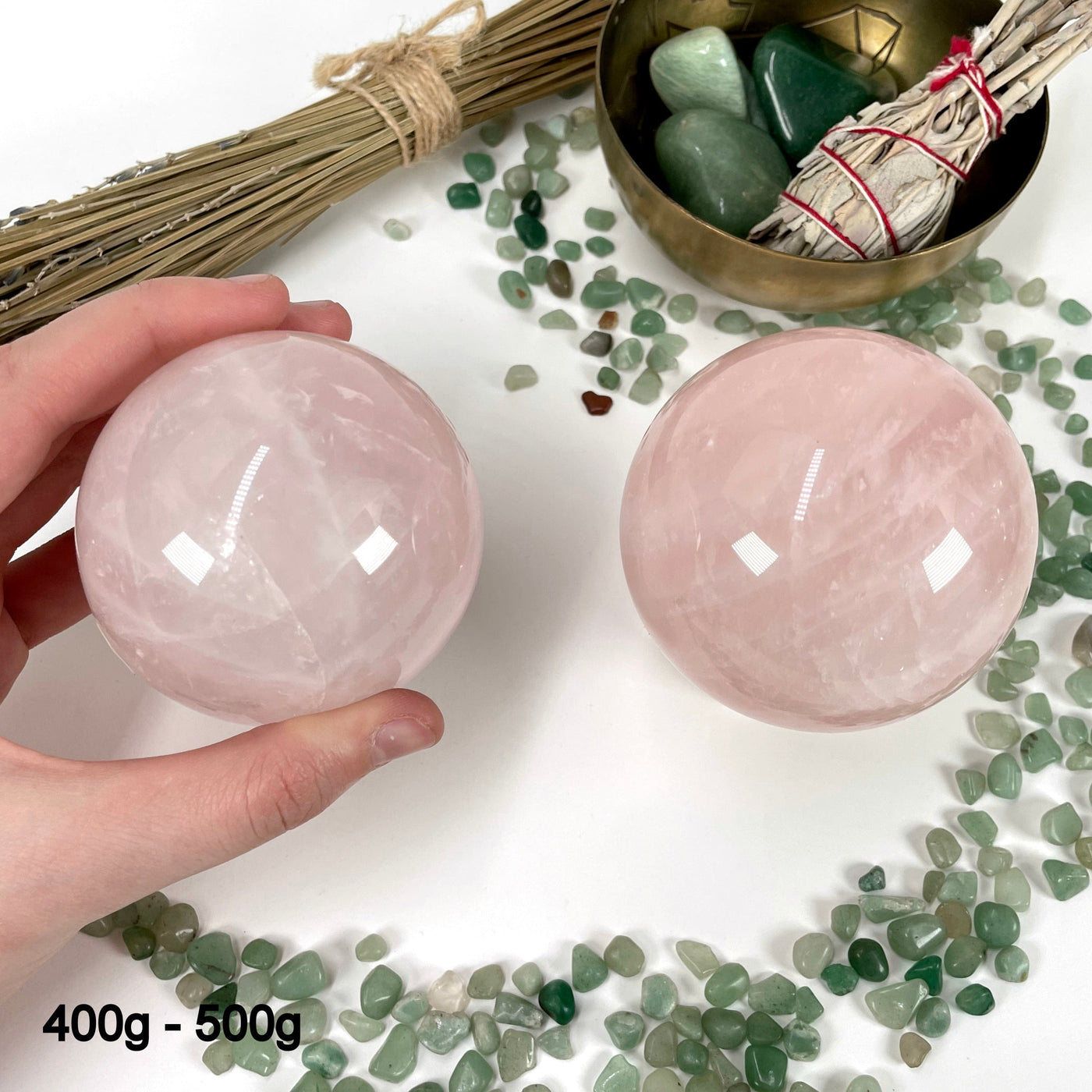 two 400g - 500g rose quartz polished spheres on display for possible variations with one of them in hand for size reference