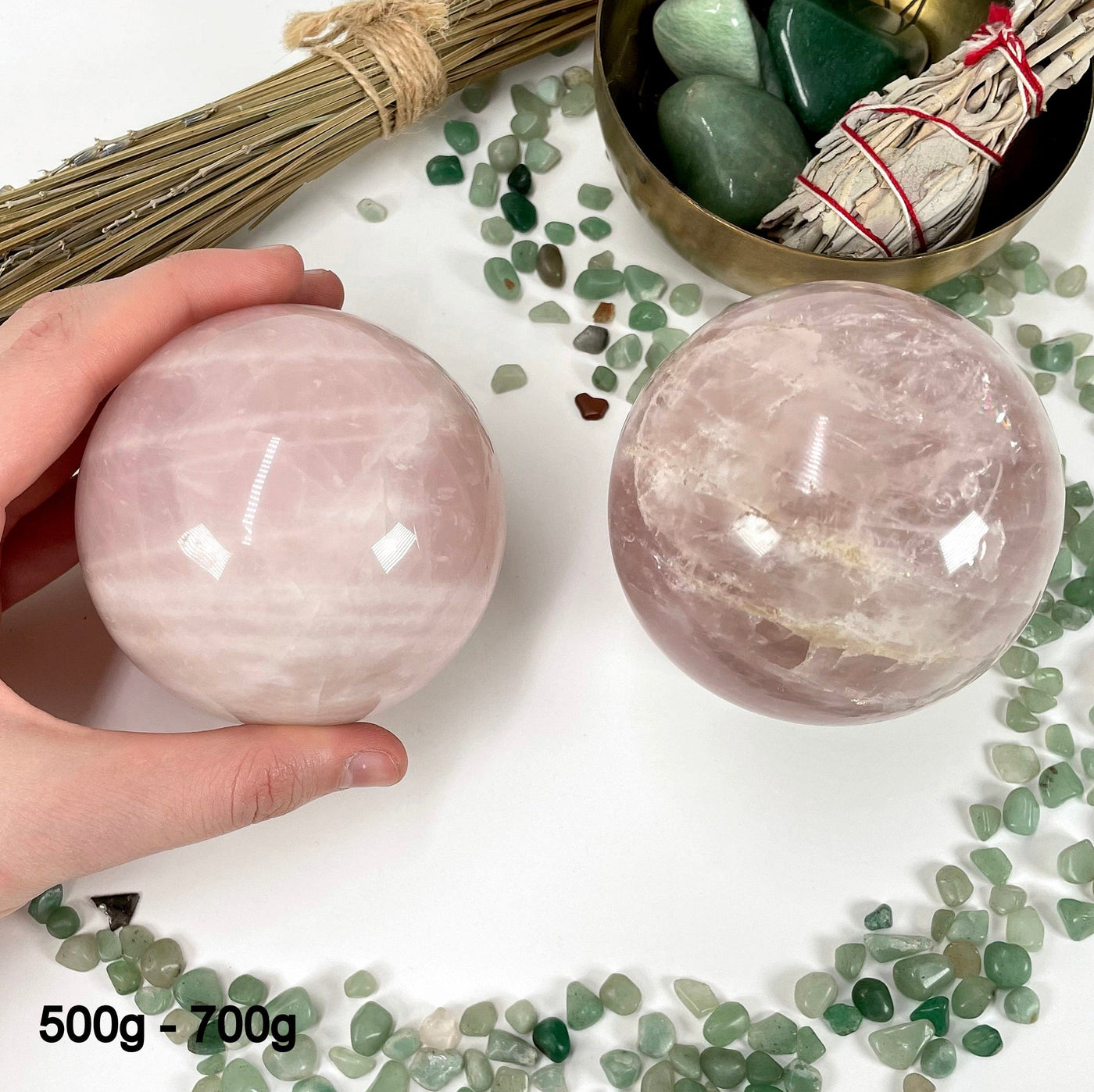 two 500g - 700g rose quartz polished spheres on display for possible variations with one of them in hand for size reference