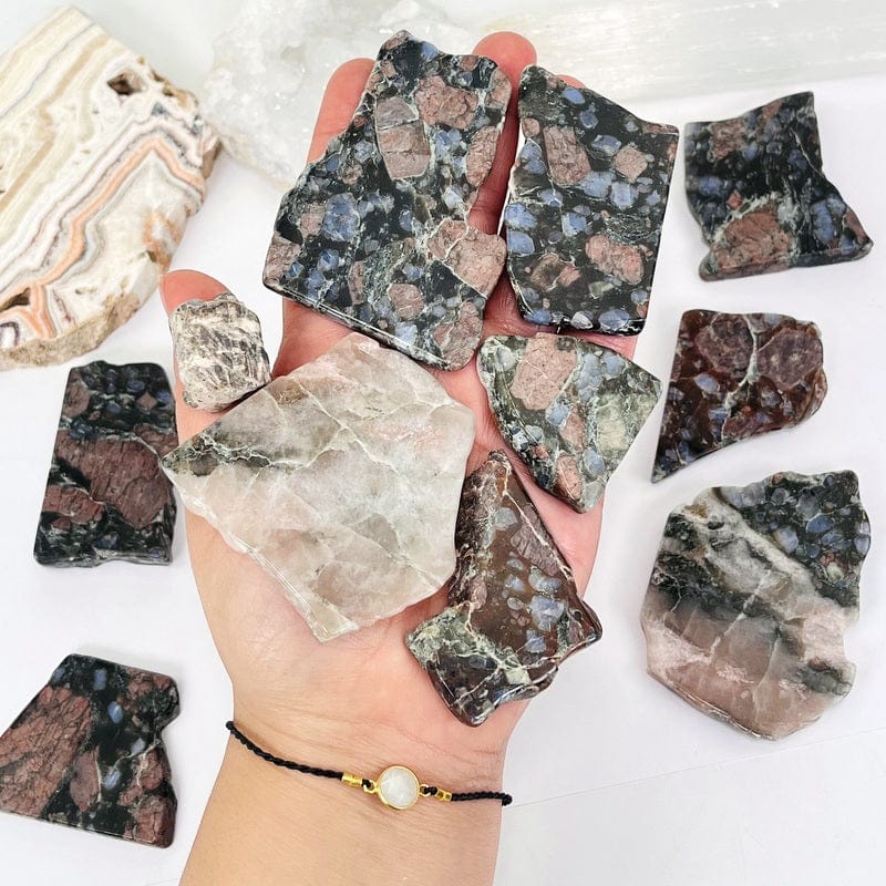 rhyolite semi-tumbled stone slabs in hand displaying the different size variations available in the one pound bag 
