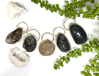 Five Agate Geode Enhydro Pendants front facing to show variety in pattern and color. Agate Geode Enhydro Pendants are on a white background with decor.