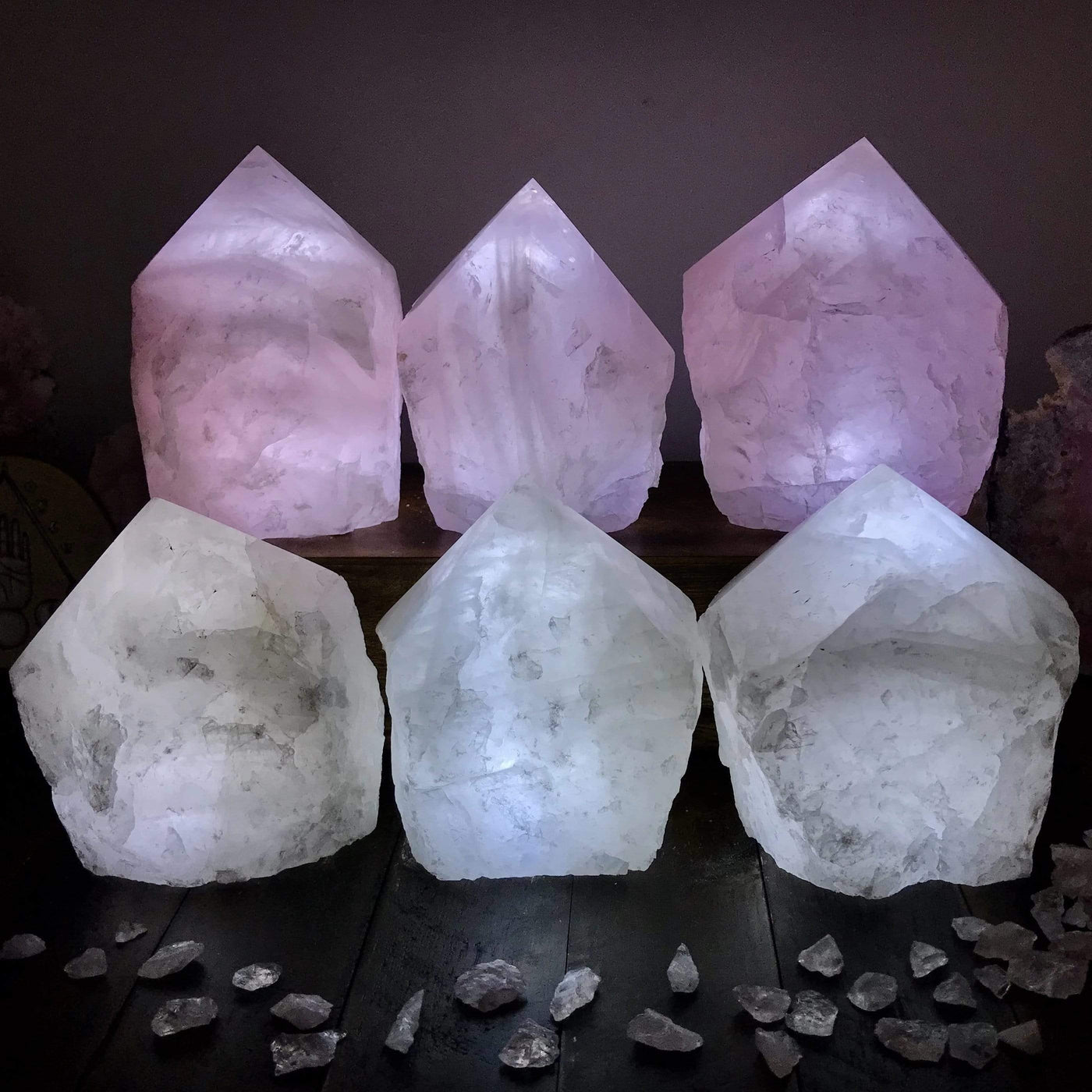 6 Rose Quartz and Crystal Lamps lit up in a dark room with other crystals as decoration
