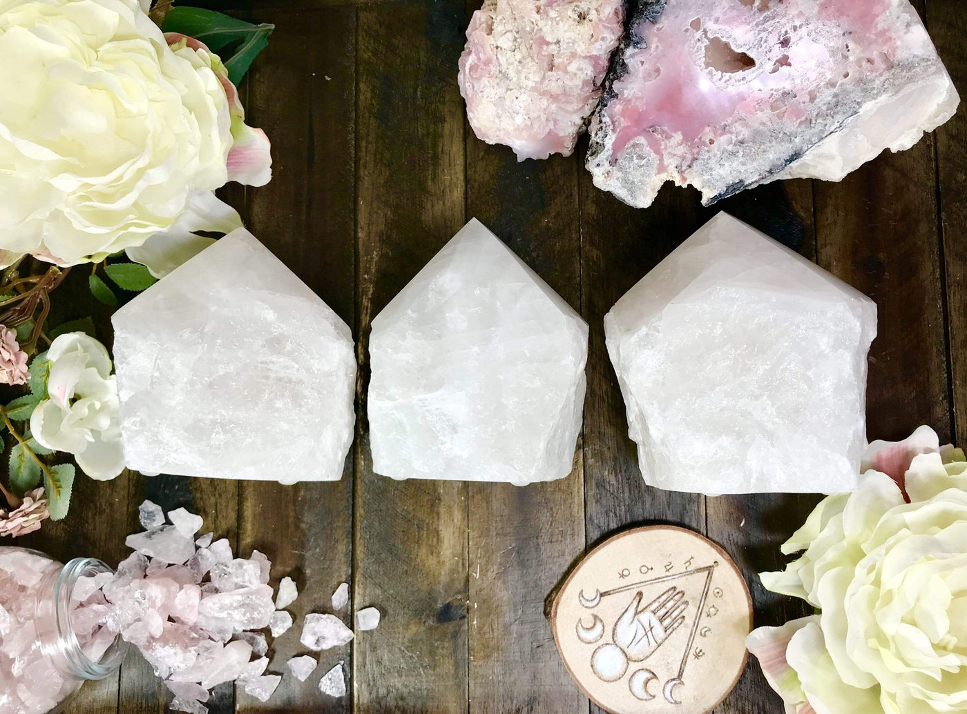 3 Crystal quartz Lamps lined up with crystals and flowers on wooden table