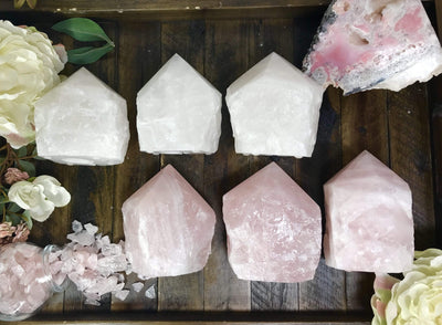 Rose Quartz and Crystal Lamps lined up with other crystals and flowers on wooden table