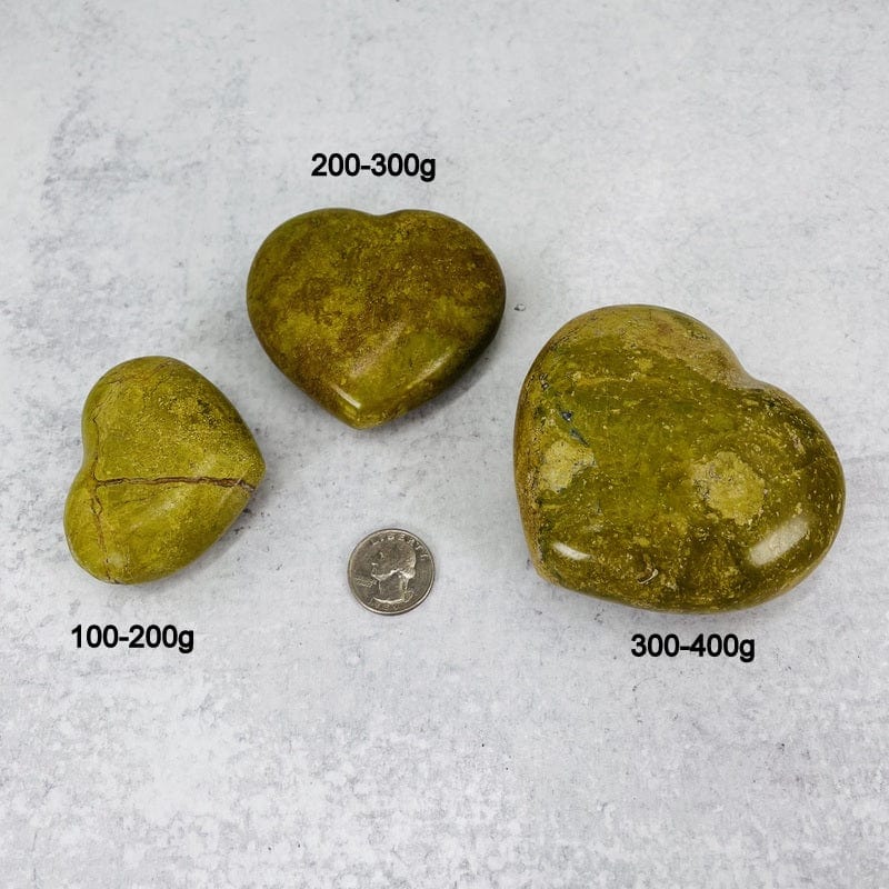 green/pistachio opal polished hearts next to a quarter for size reference and the weight in grams 