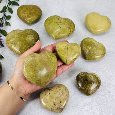 green/pistachio opal polished hearts in hand for size reference 