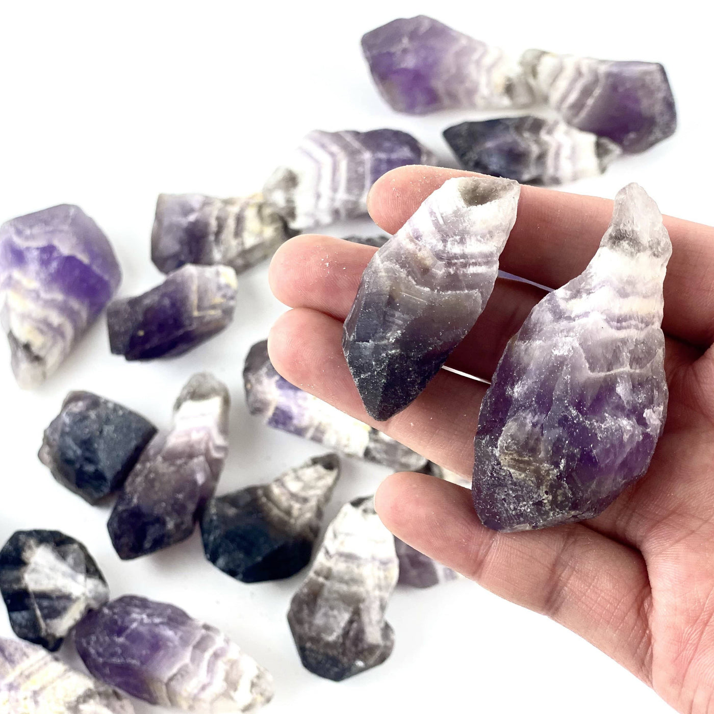 chevron amethyst assorted points on a white background.  Some are held in a hand.