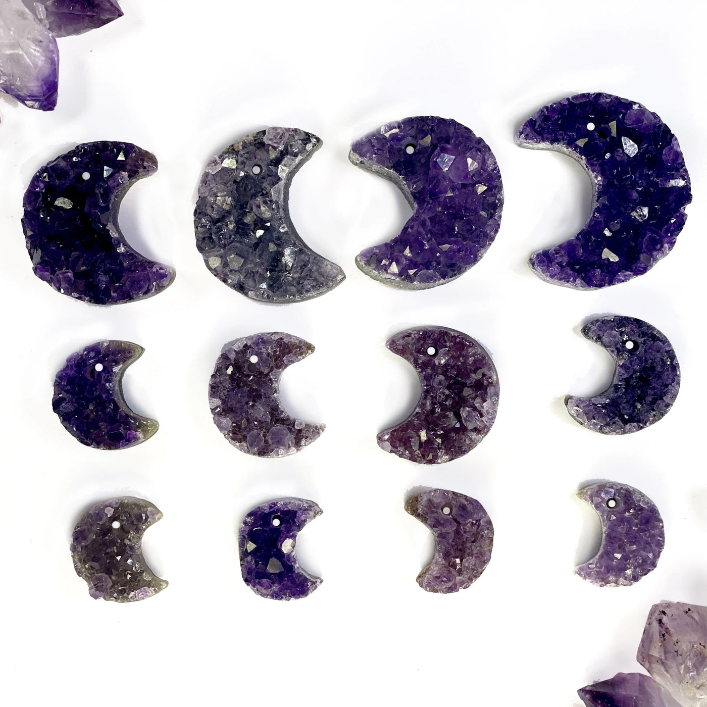 Amethyst cluster moons in assorted shades of purple to show how they vary. Also all three sizes are lined up in rows to compare them.