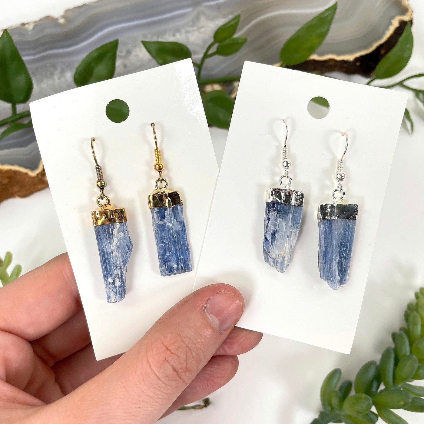 both blue kyanite earring options in their packaging in hand for option comparison