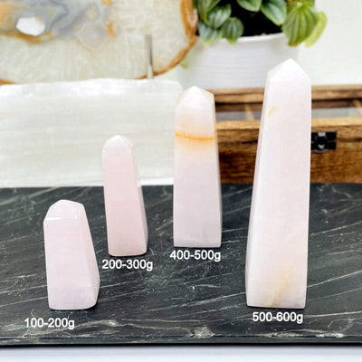 pink calcite obelisk next to its weight in grams