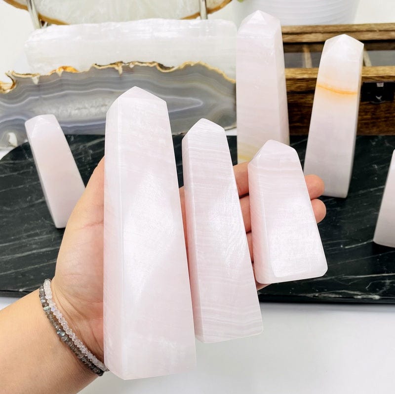 close up of pink calcite obelisk in hand 