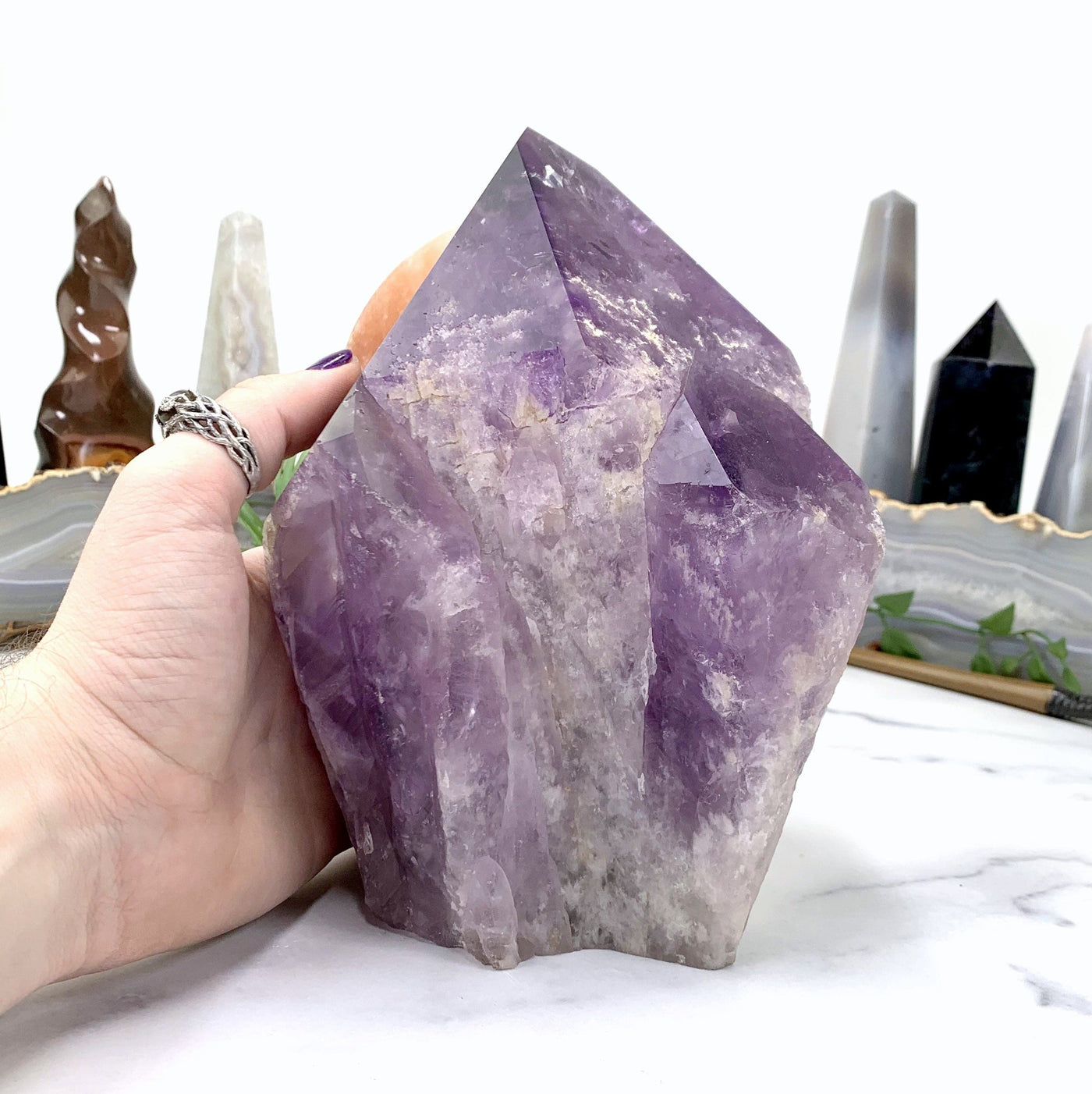 AMETHYST POINT IN HAND WITH MARBLE BACKGROUND