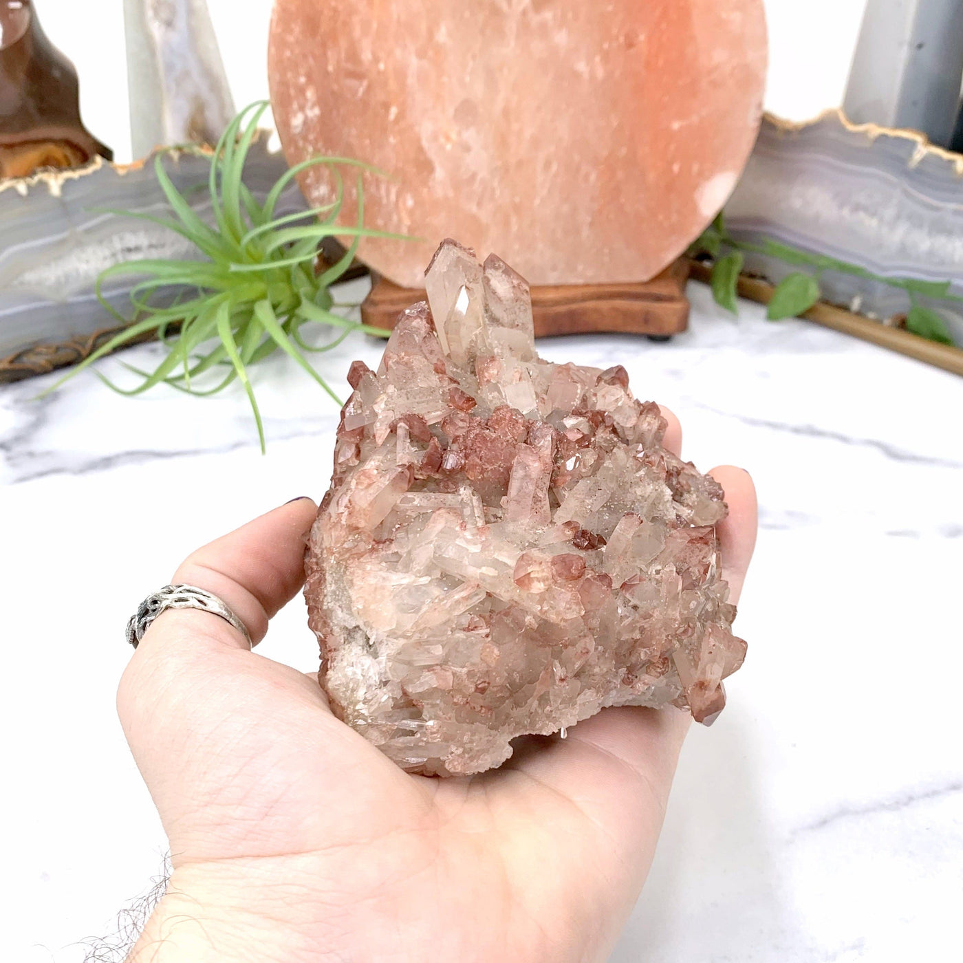 LITHIUM QUARTZ IN HAND WITH MARBLE BACKGROUND