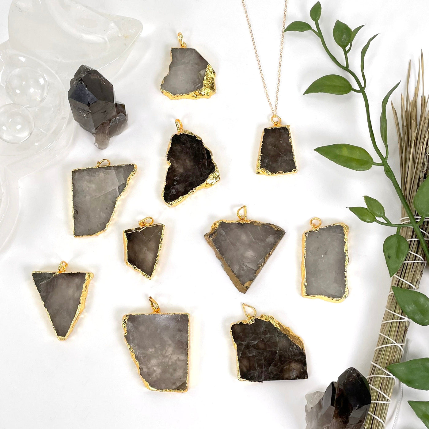 overhead view of many smokey quartz slab pendants on white background with decorations for possible variations