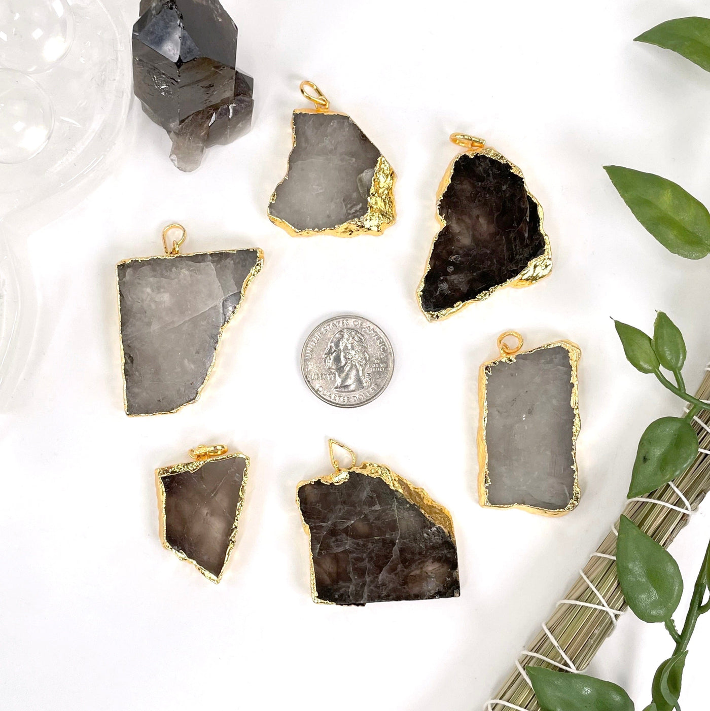 overhead view of six smokey quartz slab pendants on decorated white background with a quarter for size reference