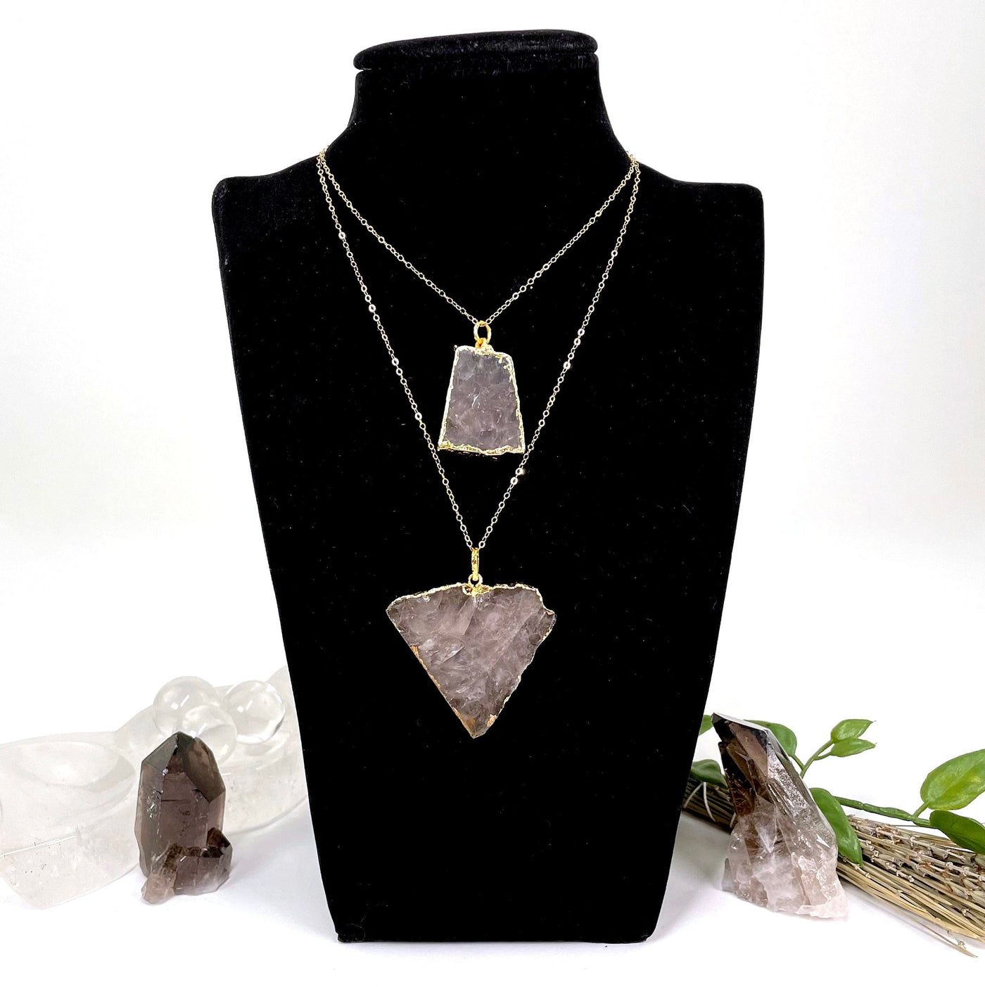 two smokey quartz slab pendants with chain hanging on bust display at different lengths