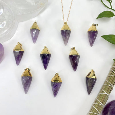 overhead view of many amethyst quartz spear pendants on white background with decorations for possible variations 