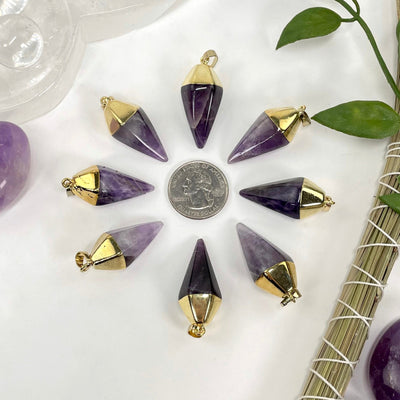 overhead view of many amethyst quartz spear pendants around a quarter in a star formation for size reference
