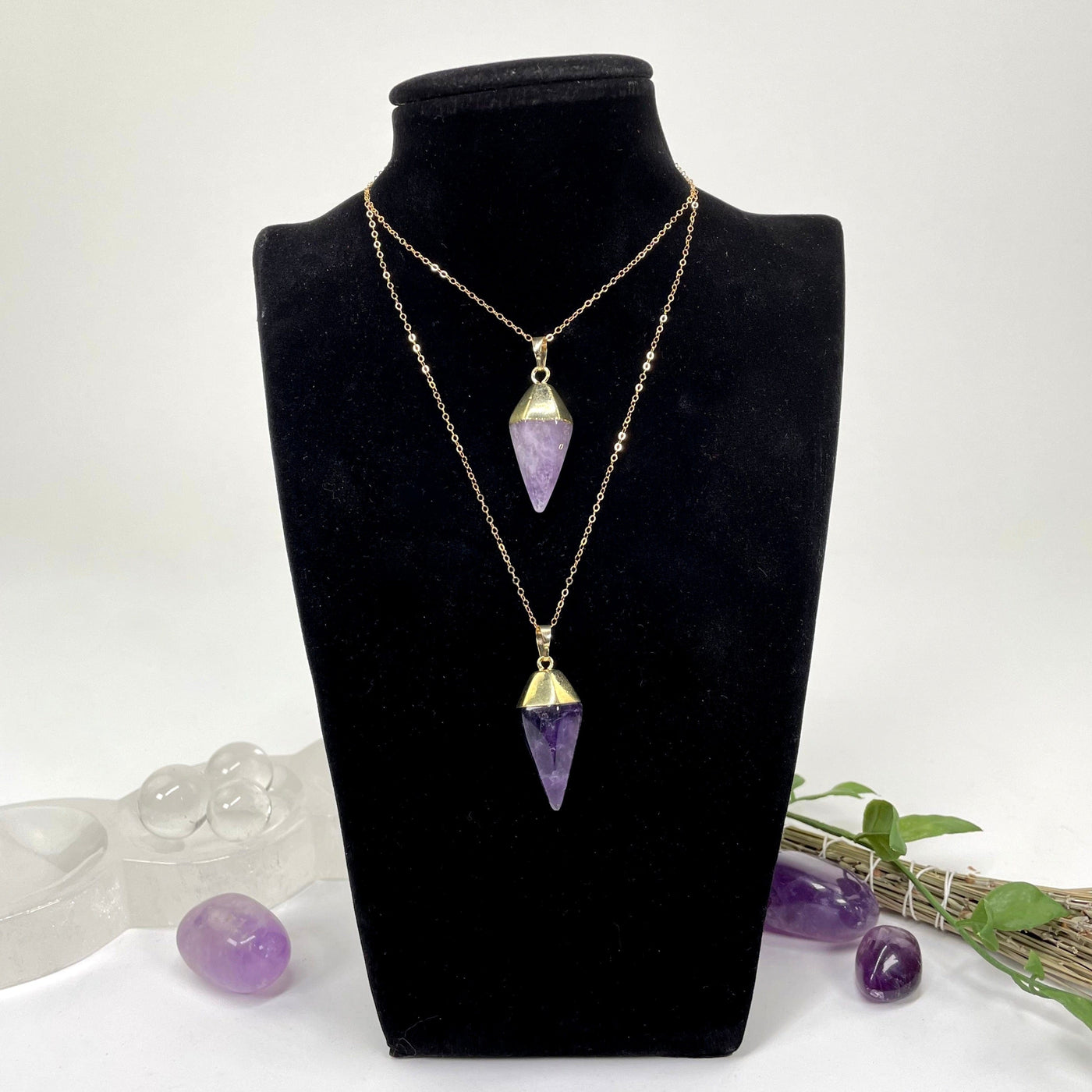 two amethyst quartz spear pendants on a chain at two different lengths on a bust display