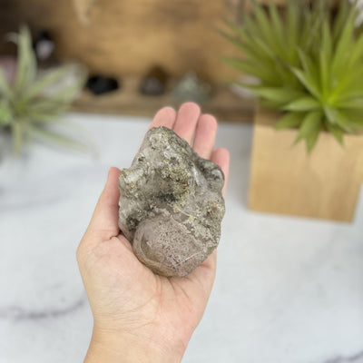 hand holding up Lodolite Quartz Cluster with decorations in the background
