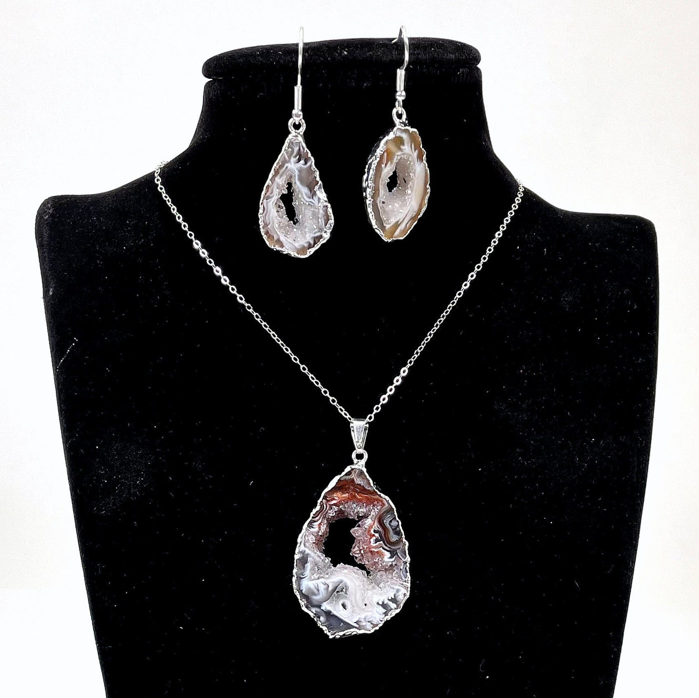 close up of one agate druzy slice pendant and earring set on bust display