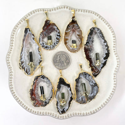 overhead view of many agate druzy slice pendants on display with quarter for size reference