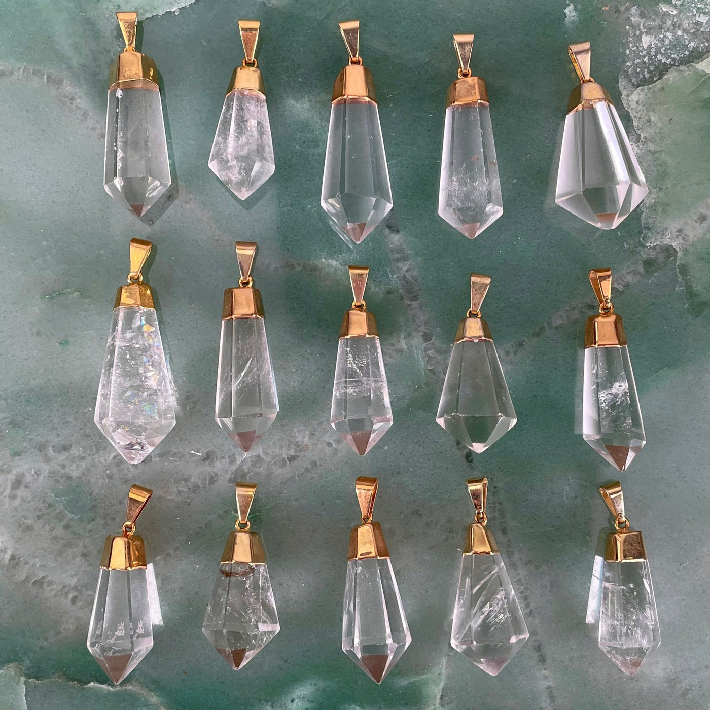 overhead view of many fancy crystal quartz point pendants in three rows for possible variations 
