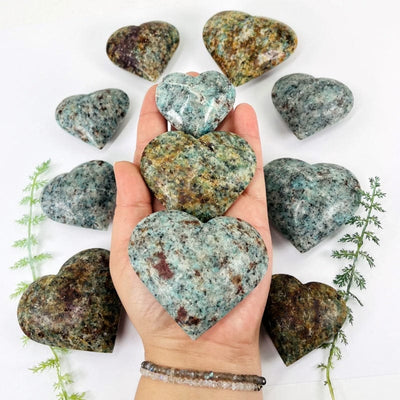 multiple amazonite polished hearts in hand for size reference 