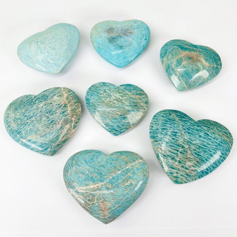 multiple amazonite polished hearts displayed on white background showing the differences in sizes and color shades  