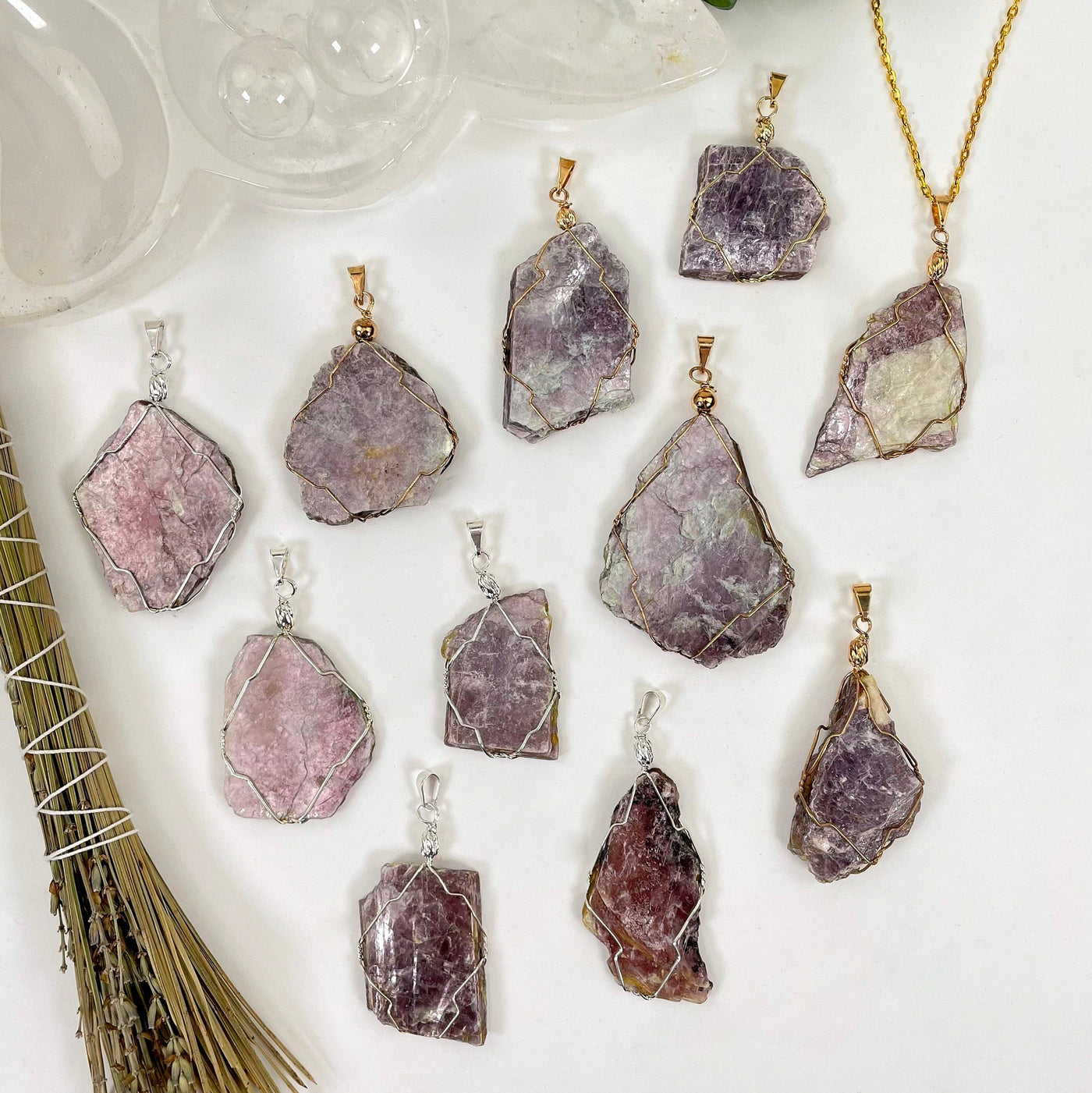 overhead view of many gold and silver purple mica wire wrapped pendants on white background for possible variations