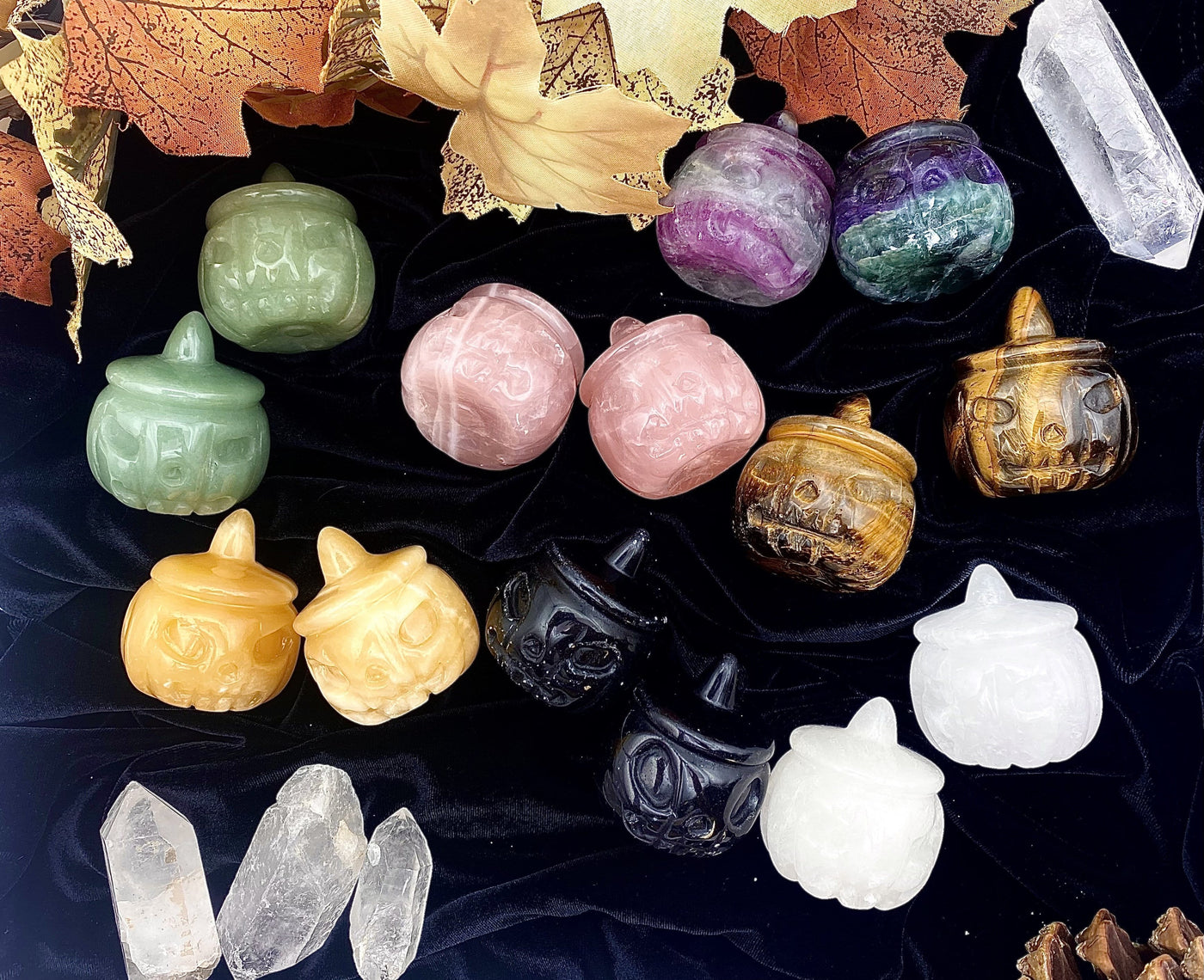 14 Carved Pumpkin Jack-o'-lantern Gemstones , 2 of each available stone, displayed on a dark velvet surface.