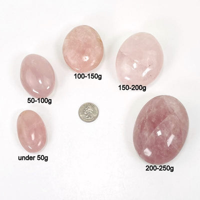 rose quartz palm stones next to their weight in grams  they come in under50g 50-100g 100-150g 150-200g 200-250g