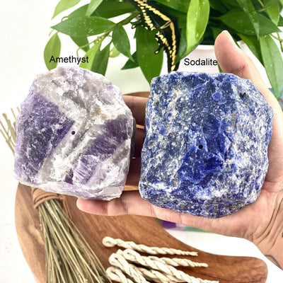 Hand holding 1 amethyst and 1 sodalite Rough Stone Incense Burner with decorations in the background