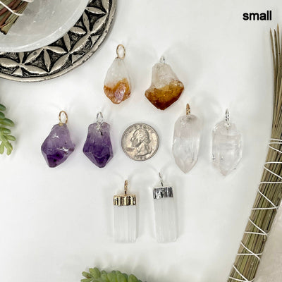 all small gemstone point pendants on white background with quarter for size reference