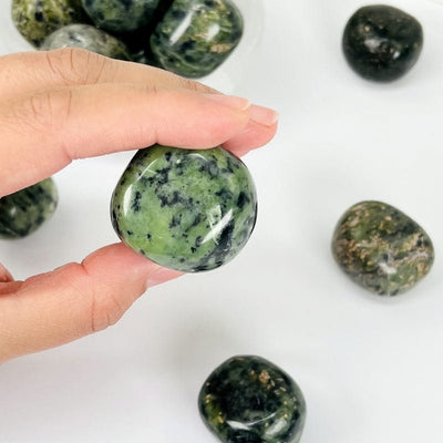 close up of a nephrite tumbled stone in hand for size reference 