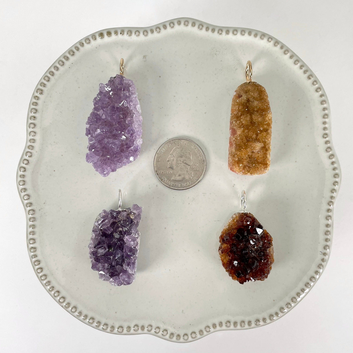 one of each amethyst druzy cluster pendant options on display with a quarter for size reference