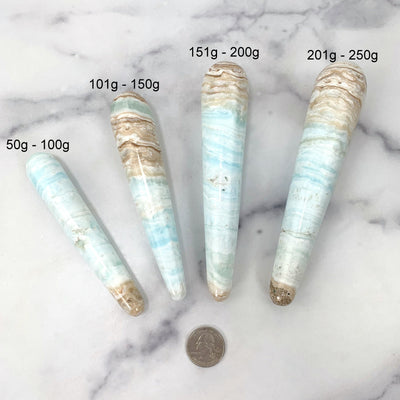 all 4 wands labeeled and laying next to a quarter on a marble background