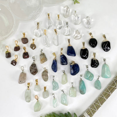 overhead view of many different tumbled gemstone pendants on display for possible variations