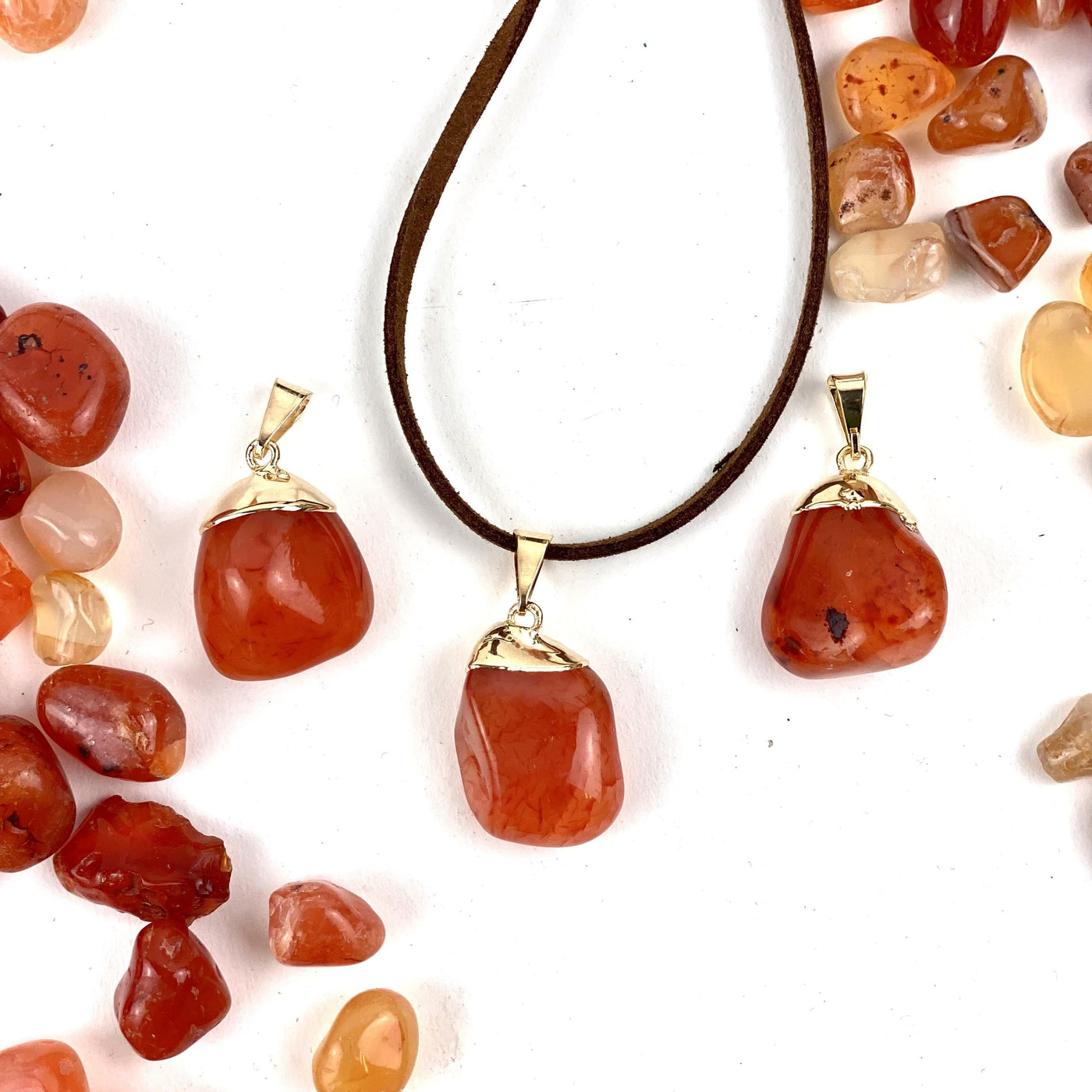 Tumbled Carnelian Pendant with Electroplated 24k Gold Cap on leather string with others on the background